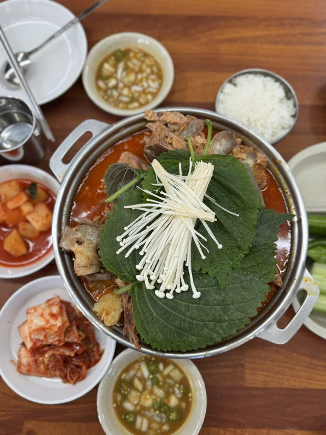 对应店铺聚合页的共享排骨汤锅实拍，可见紫苏叶、金针菇和红色汤底；拍摄日期未确认。