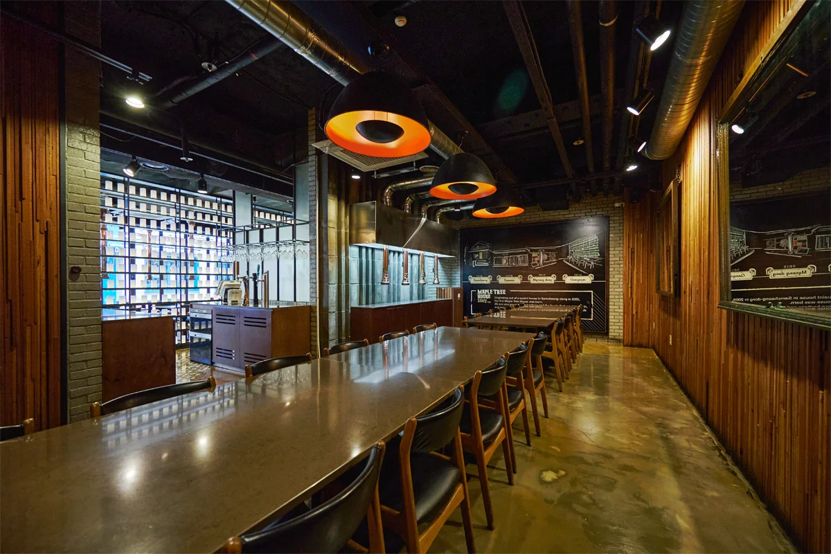 Maple Tree House 梨泰院分店官方内景：长桌、瓶墙与排烟设施。拍摄日期未标，不代表到访时桌位。