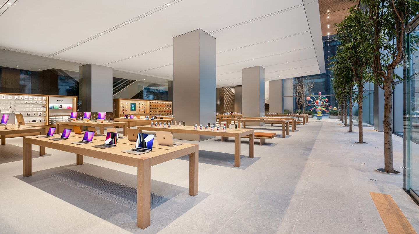 Apple明洞官方一层室内照，木桌、立柱与沿玻璃的树木。