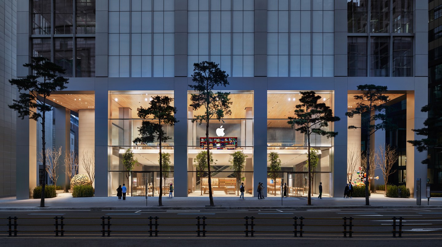 Apple明洞官方外观照，两层玻璃立面与两侧庭院；历史店图中的展品不代表当前库存。